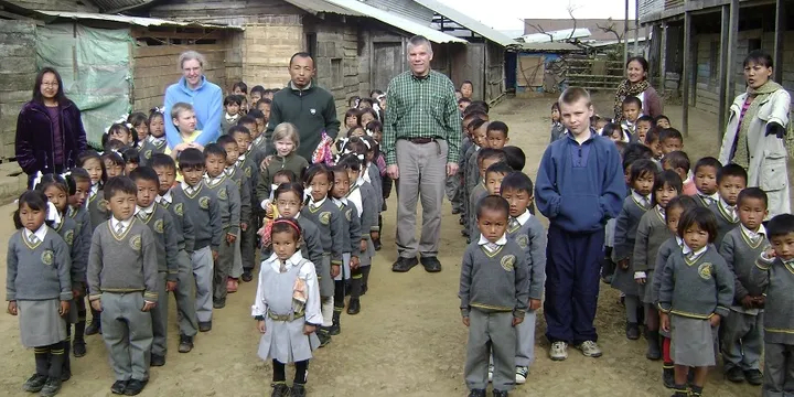 Cool-looking school sweaters help keep students warm in UNHEATED school buildings.  That's me in the middle of all those Kindergarteners, James Chizek, Founder of DestituteOrphans.org, with my bride Judy wearing light blue.  Can you pick out our three children?
